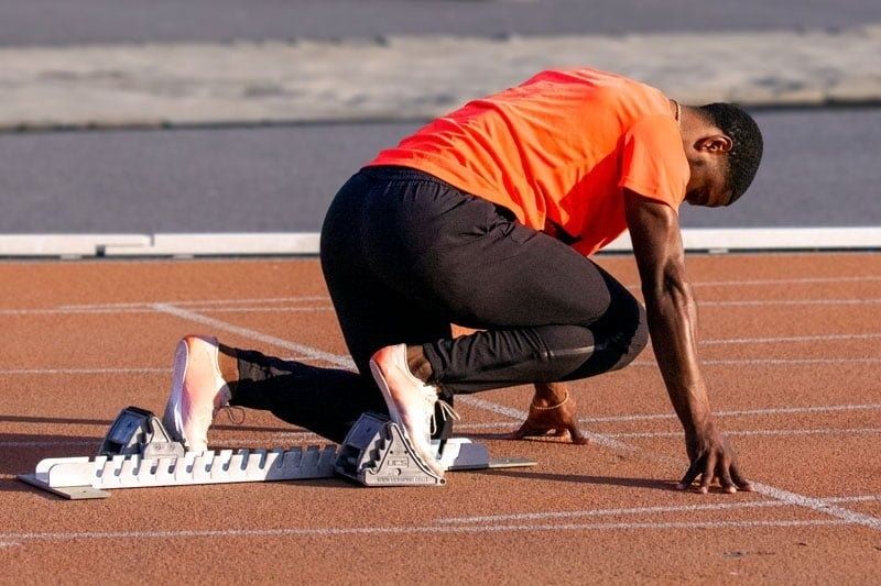 Sprinter i startposition mellan startblock på löparbana